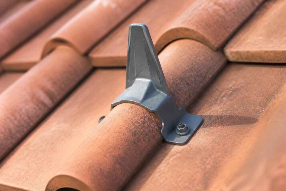 Metalowy element mocujący zamontowany na profilowanej dachówce w odcieniu terakoty